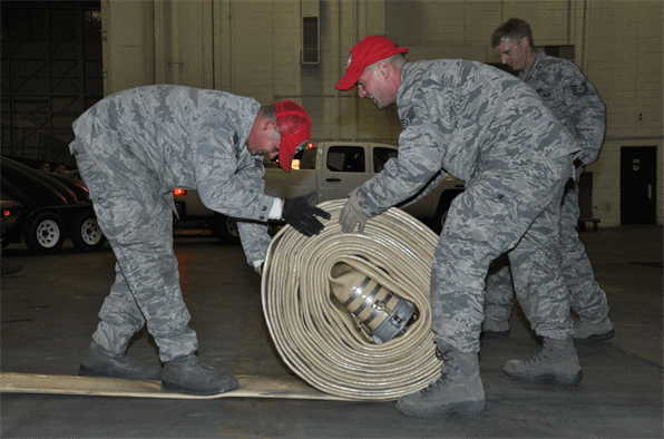 Los ingenieros de la fuerza aérea enrollan la manguera de suministro