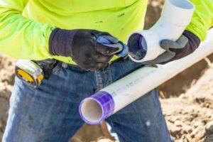 Pipefitter holding pipe with adhesive